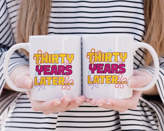 White ceramic mug with colorful “Thirty Years Later…” text inspired by cartoon title cards, held in hand by a smiling woman – perfect 30th birthday gift
